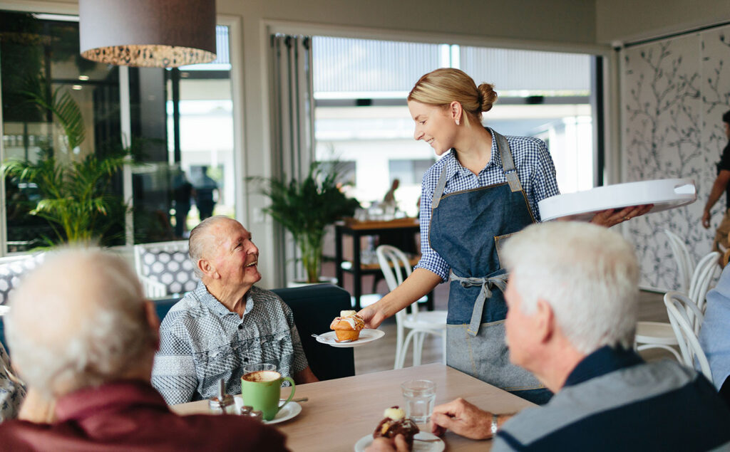 Elderly man being served food at a cafe | Featured Image for the Disability Aged Care Page of NewDirection Care.