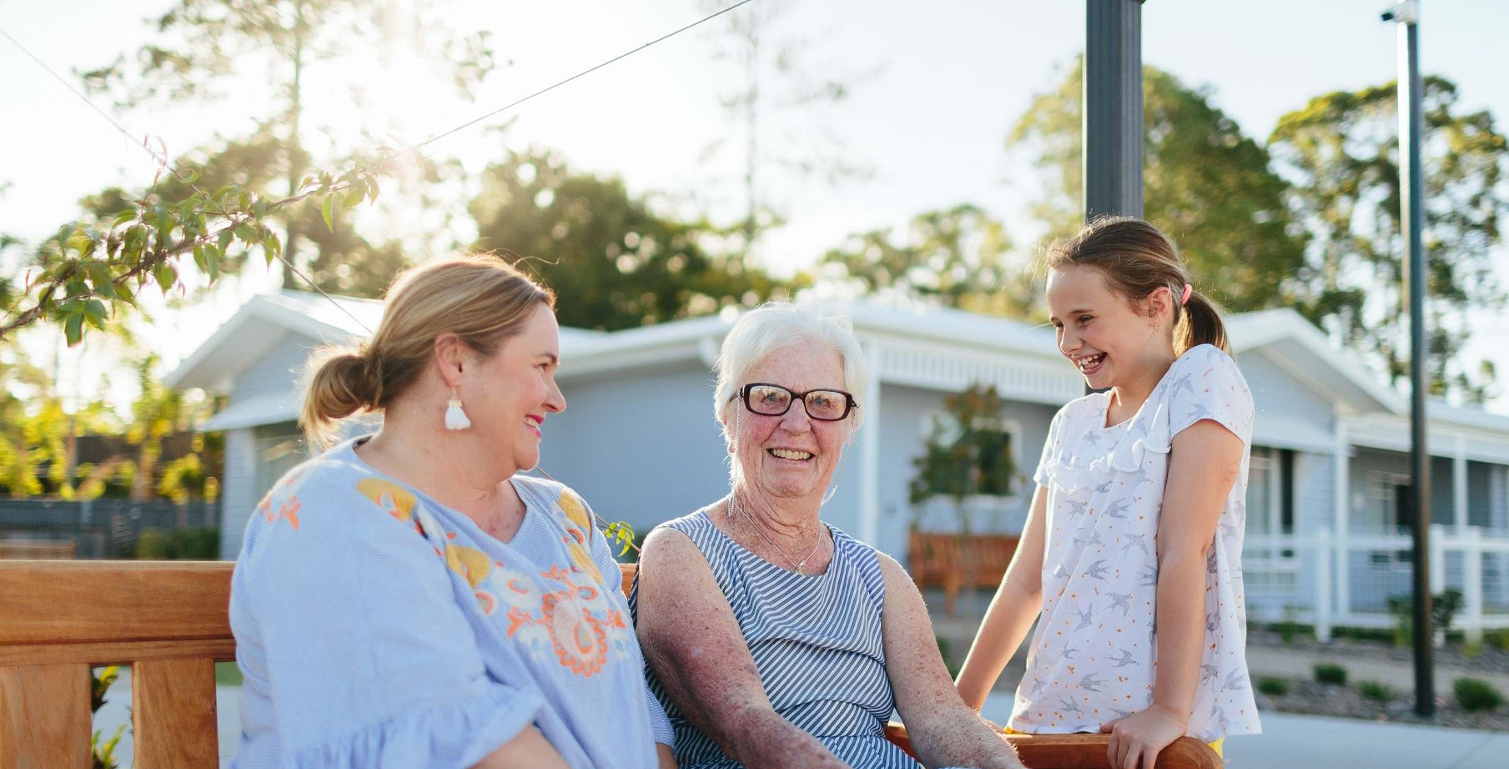 Family sitting on a bench togethter smiling | Featured Image for the Health and Wellness Clinic Page of NewDirection Care.